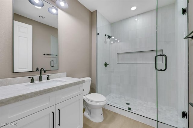 bathroom featuring vanity, a shower stall, toilet, and visible vents