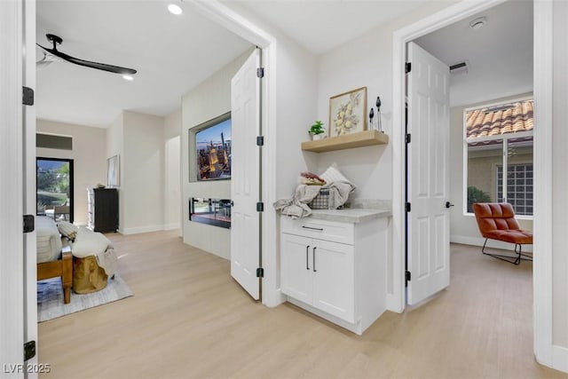 hall featuring baseboards, light wood-type flooring, and visible vents