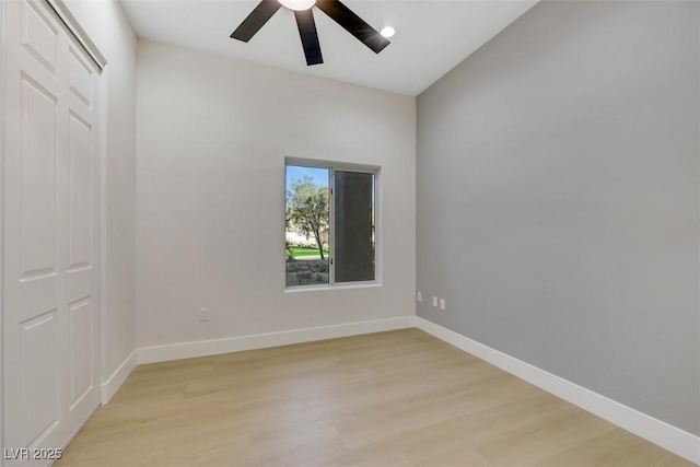 empty room with light wood-type flooring, a ceiling fan, and baseboards