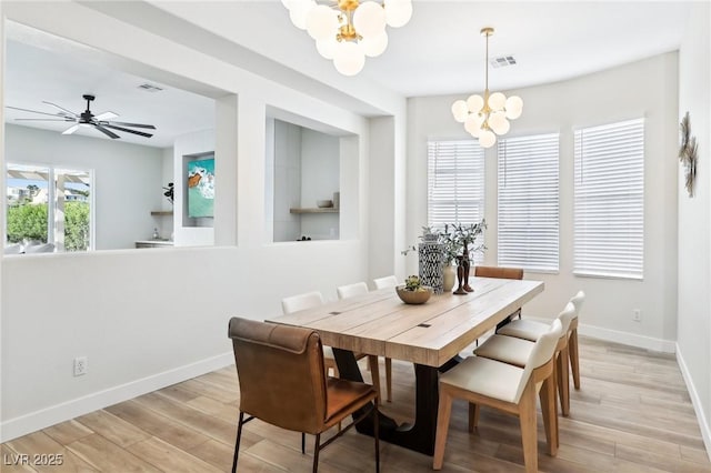 dining space with baseboards, visible vents, light wood-type flooring, and a notable chandelier
