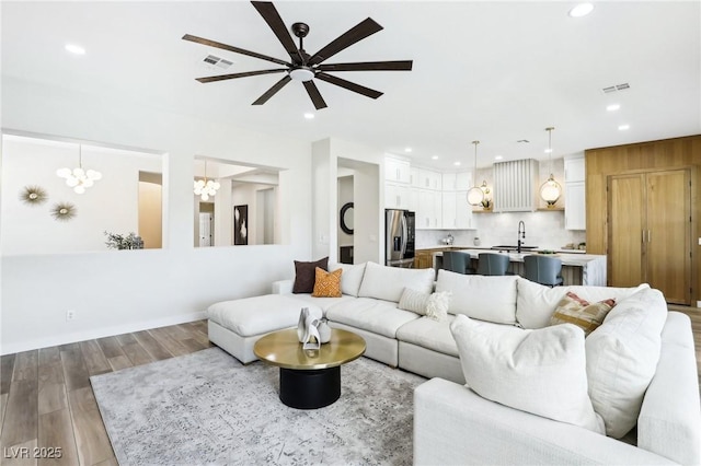 living area featuring ceiling fan with notable chandelier, recessed lighting, wood finished floors, and visible vents