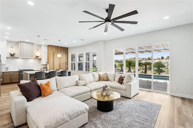 living room featuring recessed lighting, light wood-style flooring, ceiling fan, and baseboards