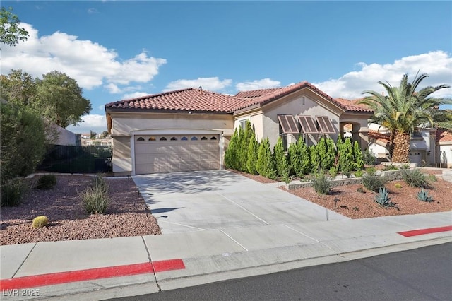 mediterranean / spanish-style home with an attached garage, stucco siding, a tiled roof, and concrete driveway