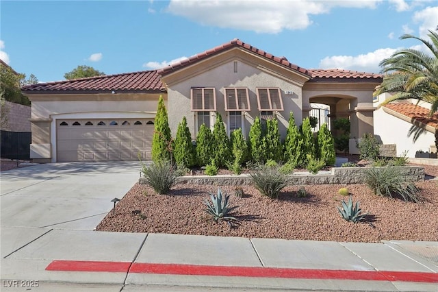 mediterranean / spanish house with an attached garage, stucco siding, driveway, and a tile roof