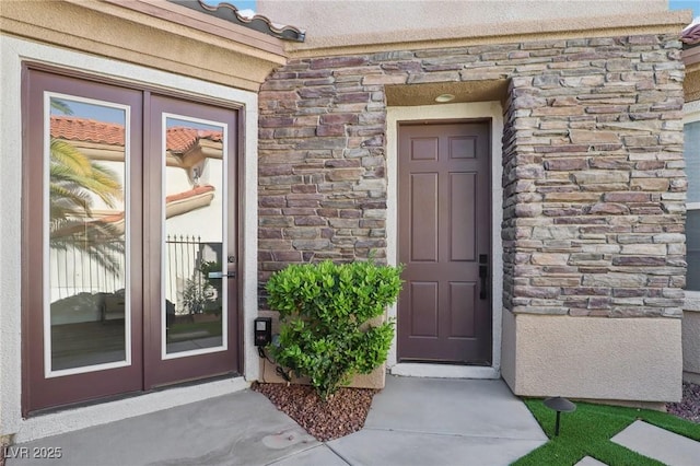property entrance with french doors, stucco siding, and stone siding