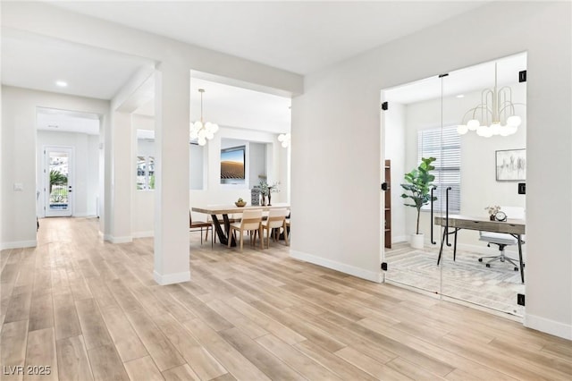 interior space featuring an inviting chandelier, plenty of natural light, and light wood finished floors