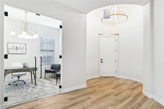 interior space featuring baseboards, a notable chandelier, and light wood-style floors