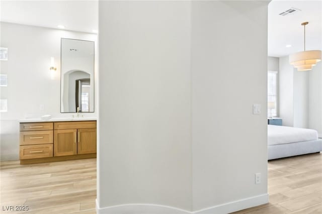 corridor with recessed lighting, visible vents, a sink, and light wood-type flooring