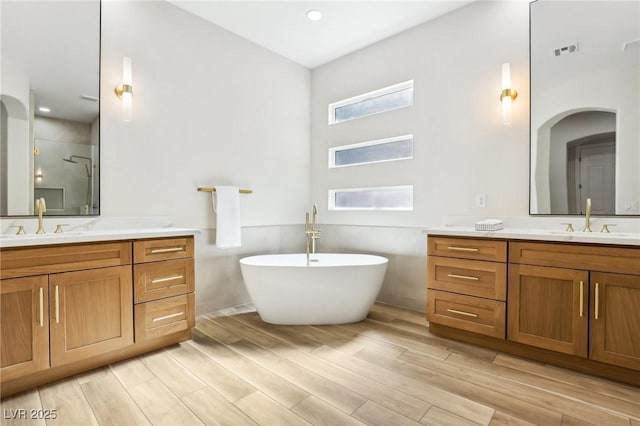 full bathroom featuring a sink, a stall shower, wood finished floors, and visible vents