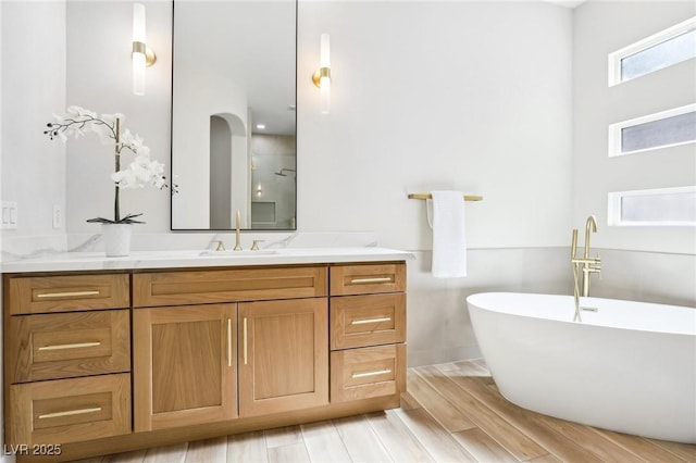 full bath with vanity, a soaking tub, and wood finish floors
