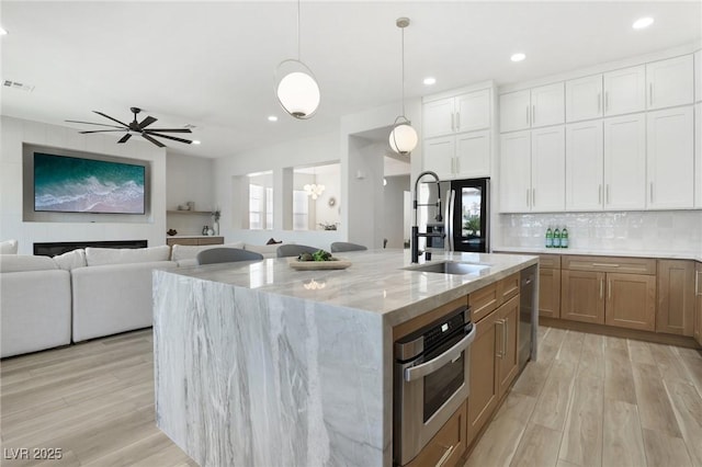kitchen featuring recessed lighting, light stone counters, a sink, and stainless steel appliances