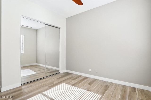 unfurnished bedroom featuring a closet, baseboards, ceiling fan, and wood finished floors