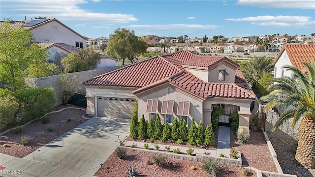 mediterranean / spanish home with a tile roof, a residential view, concrete driveway, an attached garage, and stucco siding