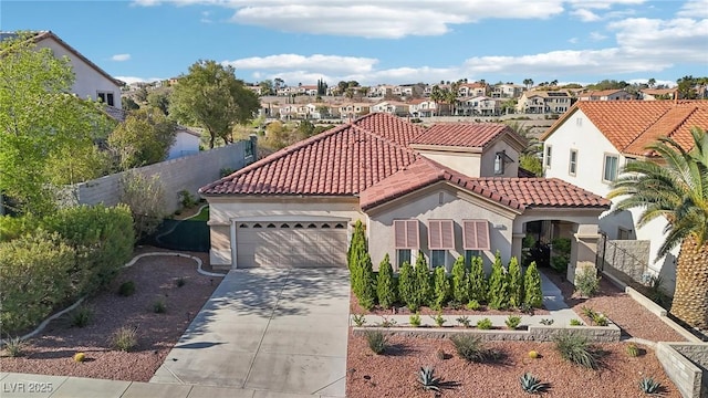 mediterranean / spanish house featuring a residential view, fence, a garage, stucco siding, and concrete driveway