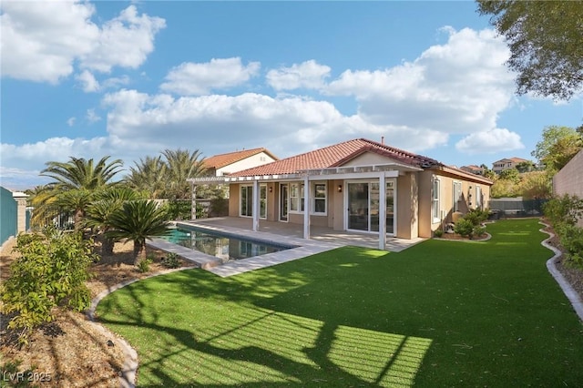 rear view of house with a patio, an outdoor pool, stucco siding, a tiled roof, and a lawn