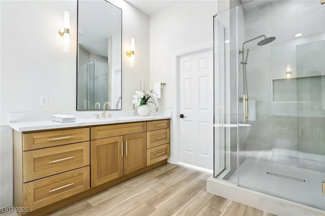 bathroom with an enclosed shower, vanity, and wood finished floors