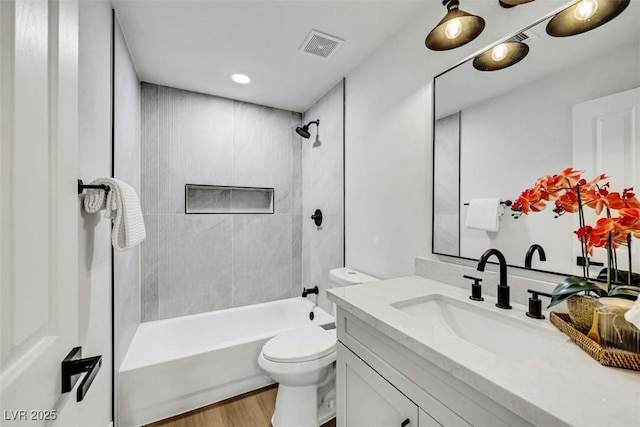 bathroom featuring vanity, visible vents, tub / shower combination, wood finished floors, and toilet