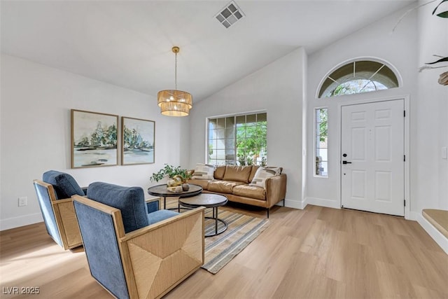 foyer entrance featuring baseboards, visible vents, vaulted ceiling, and light wood-type flooring