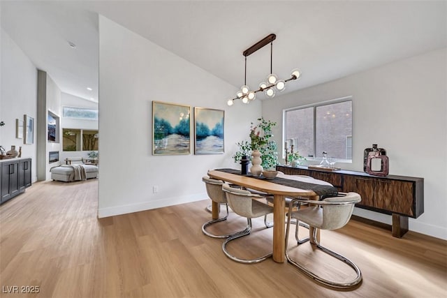 dining area with baseboards, a healthy amount of sunlight, high vaulted ceiling, and light wood-type flooring