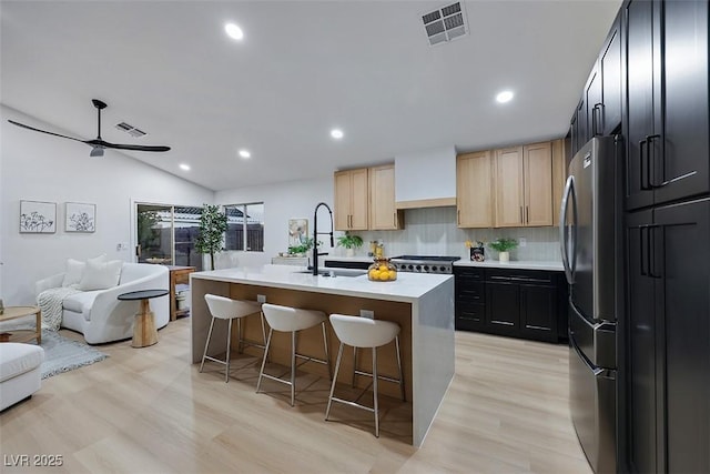 kitchen featuring visible vents, a sink, light countertops, freestanding refrigerator, and open floor plan