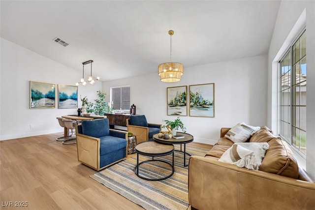 living area featuring baseboards, a notable chandelier, light wood-style flooring, and visible vents