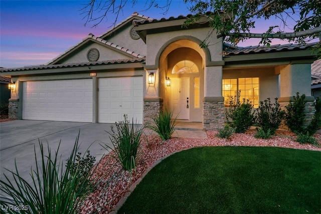 mediterranean / spanish-style home featuring a garage, stucco siding, driveway, and stone siding