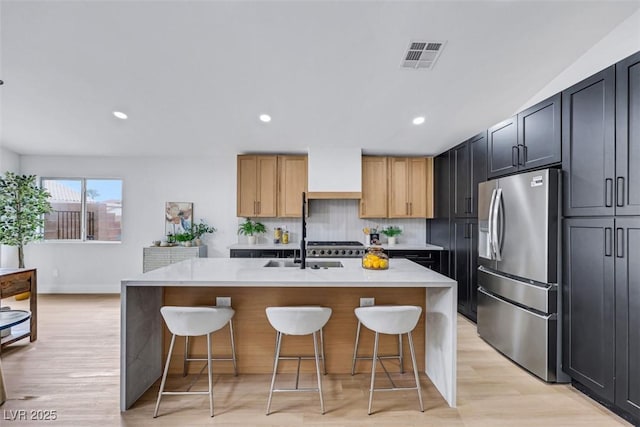 kitchen featuring light countertops, light wood finished floors, a kitchen bar, and stainless steel fridge with ice dispenser