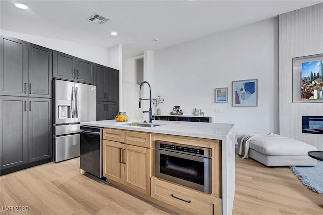 kitchen featuring a sink, stainless steel appliances, light wood finished floors, and visible vents