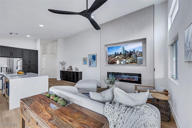 living area featuring a ceiling fan, light wood-style flooring, and visible vents