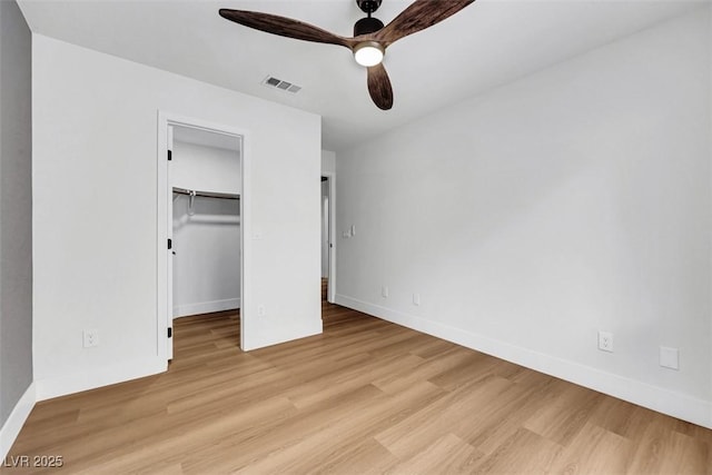 unfurnished bedroom with light wood-style floors, a spacious closet, baseboards, and visible vents