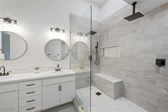 full bathroom featuring double vanity, a walk in shower, and a sink