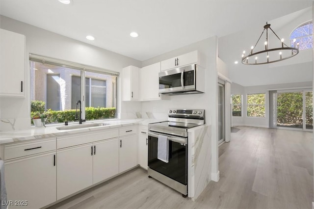 kitchen with white cabinets, a sink, light wood-style floors, stainless steel appliances, and recessed lighting