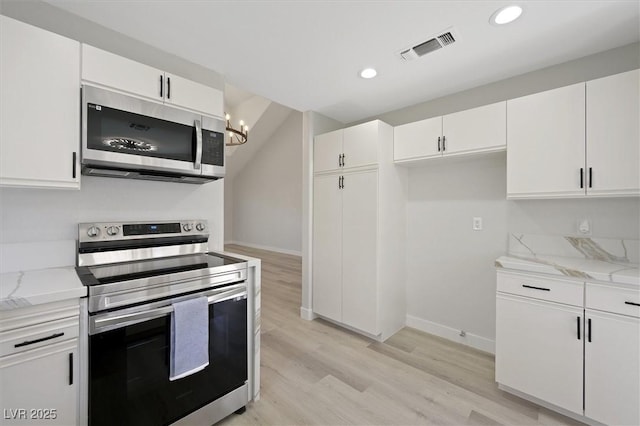 kitchen featuring visible vents, light wood-type flooring, white cabinets, light stone counters, and appliances with stainless steel finishes