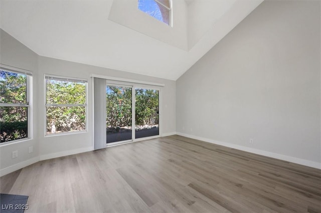 empty room featuring baseboards, high vaulted ceiling, and wood finished floors