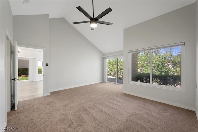 carpeted spare room featuring high vaulted ceiling, baseboards, a ceiling fan, and a wealth of natural light