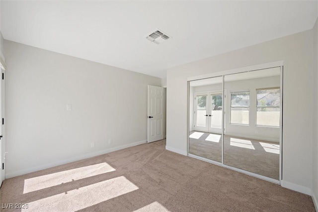unfurnished room with carpet floors, baseboards, visible vents, and french doors