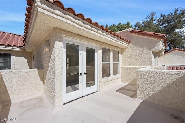 exterior space featuring a tiled roof, stucco siding, and french doors