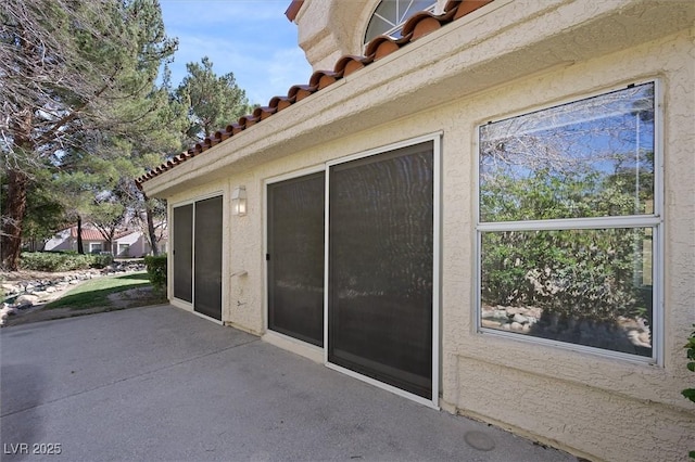 view of property exterior with a tile roof, a patio area, and stucco siding