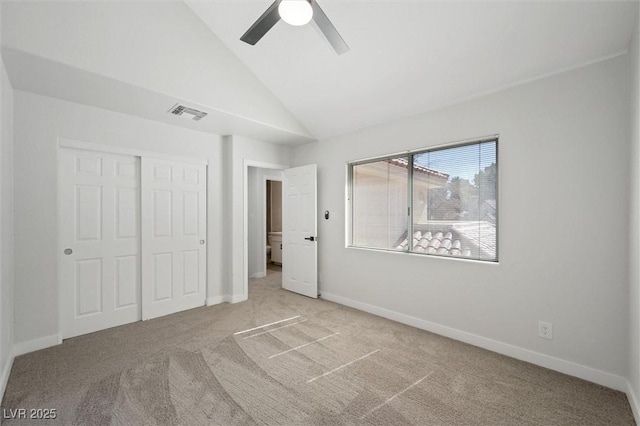 unfurnished bedroom featuring visible vents, baseboards, a closet, lofted ceiling, and carpet
