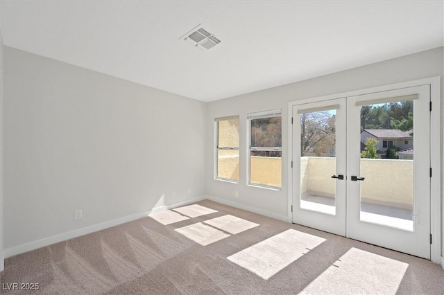 spare room featuring baseboards, french doors, light colored carpet, and visible vents