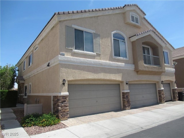 view of front of house featuring a garage, stucco siding, and stone siding