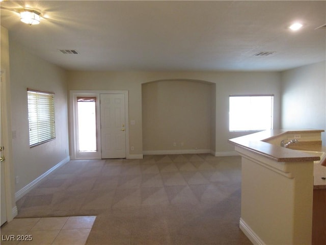 interior space featuring baseboards, light colored carpet, and visible vents