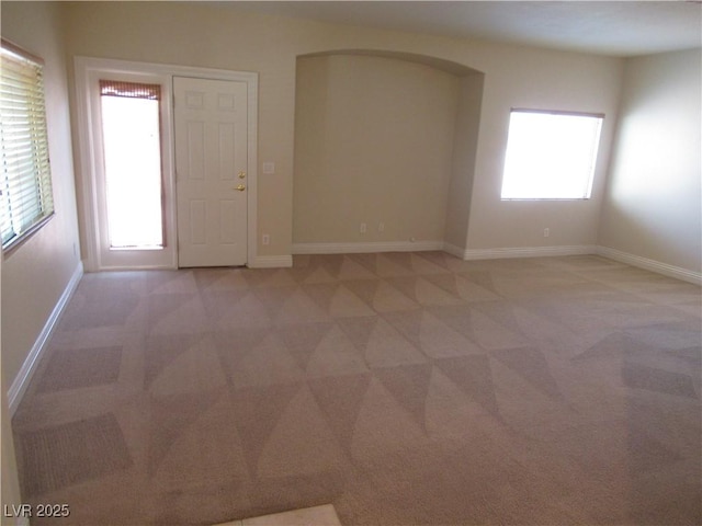 empty room with baseboards, a healthy amount of sunlight, and light carpet