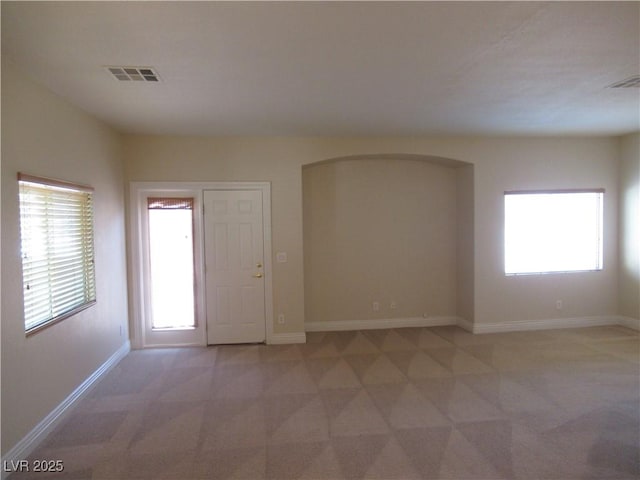 spare room featuring baseboards, visible vents, and light carpet