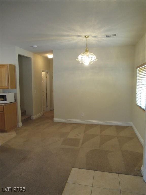 interior space with baseboards, an inviting chandelier, and light carpet