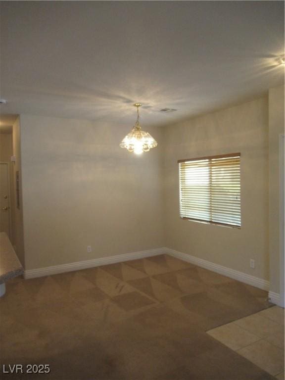 spare room with baseboards and a chandelier