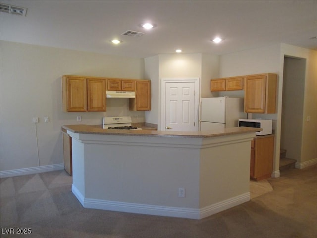 kitchen featuring visible vents, under cabinet range hood, white appliances, and light colored carpet
