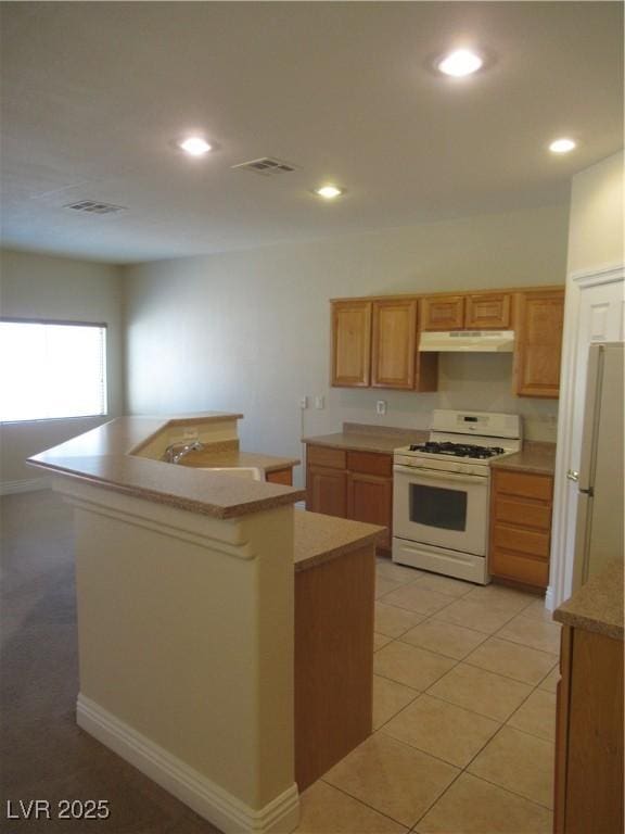 kitchen with visible vents, white appliances, light countertops, under cabinet range hood, and a sink