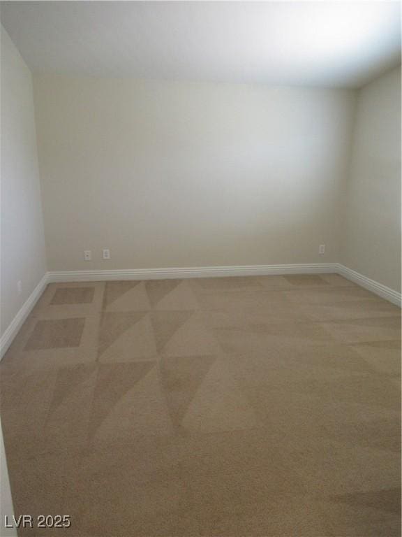 spare room with baseboards and light colored carpet