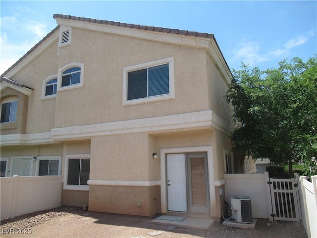 back of house with stucco siding, central AC unit, fence, and a patio